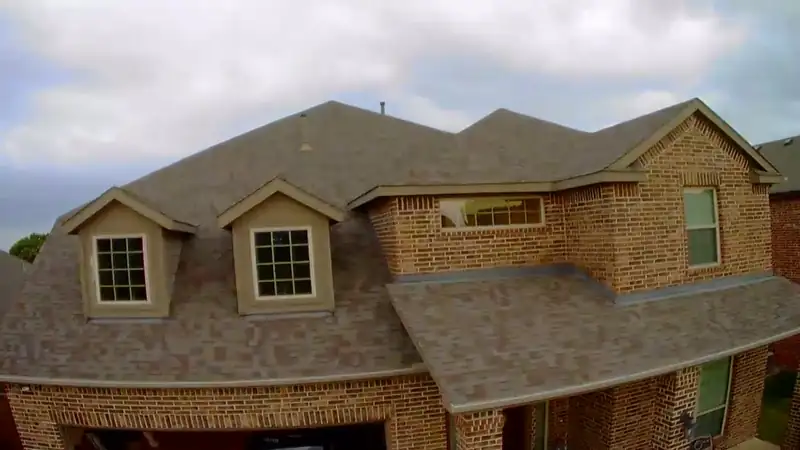 Drone photo of a two-story brick home's roof during an inspection