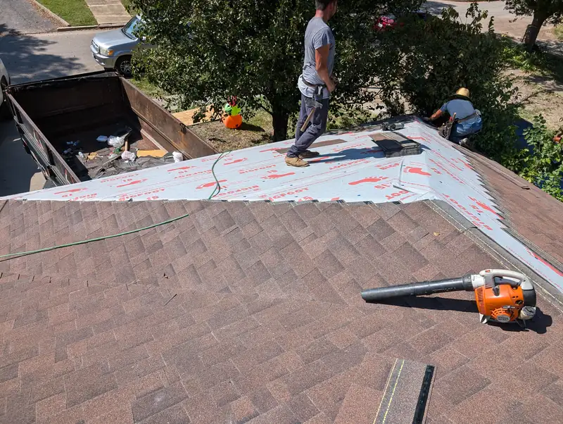 Roof tear-off in progress with a dumpster in the driveway